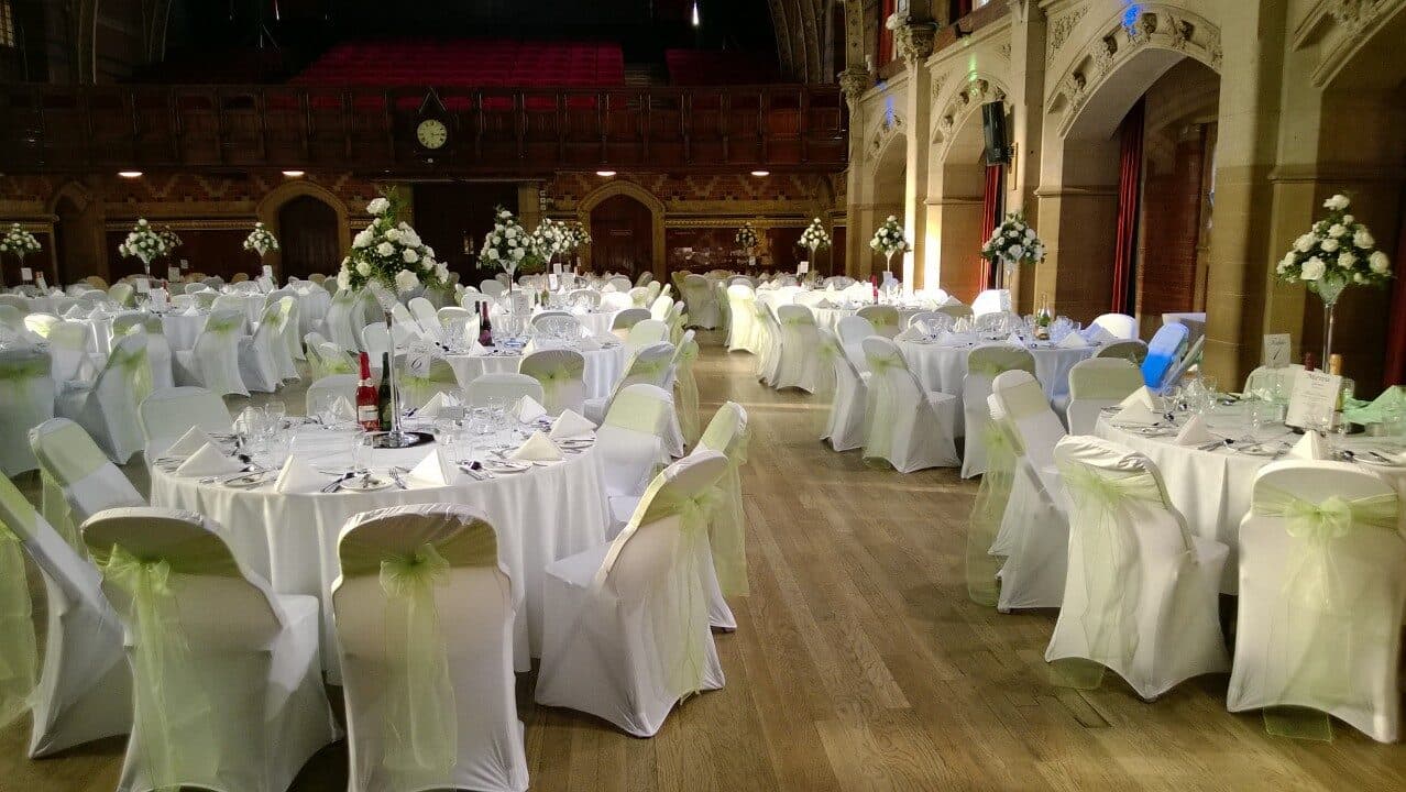 Large hall set with white chair covers, lime green organza sashes and tall white centrepieces